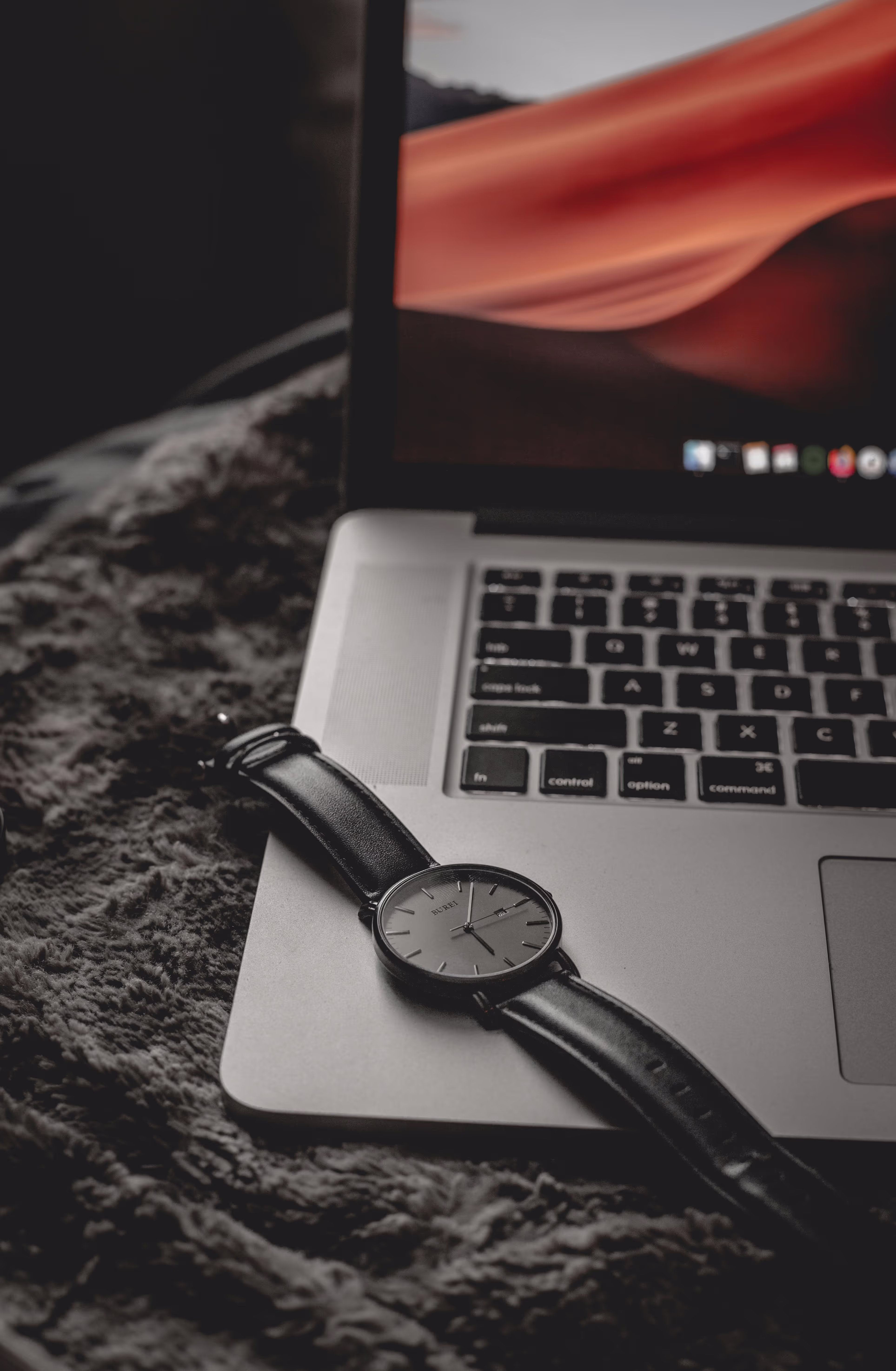 Close up of a wrist watch laying on a laptop.